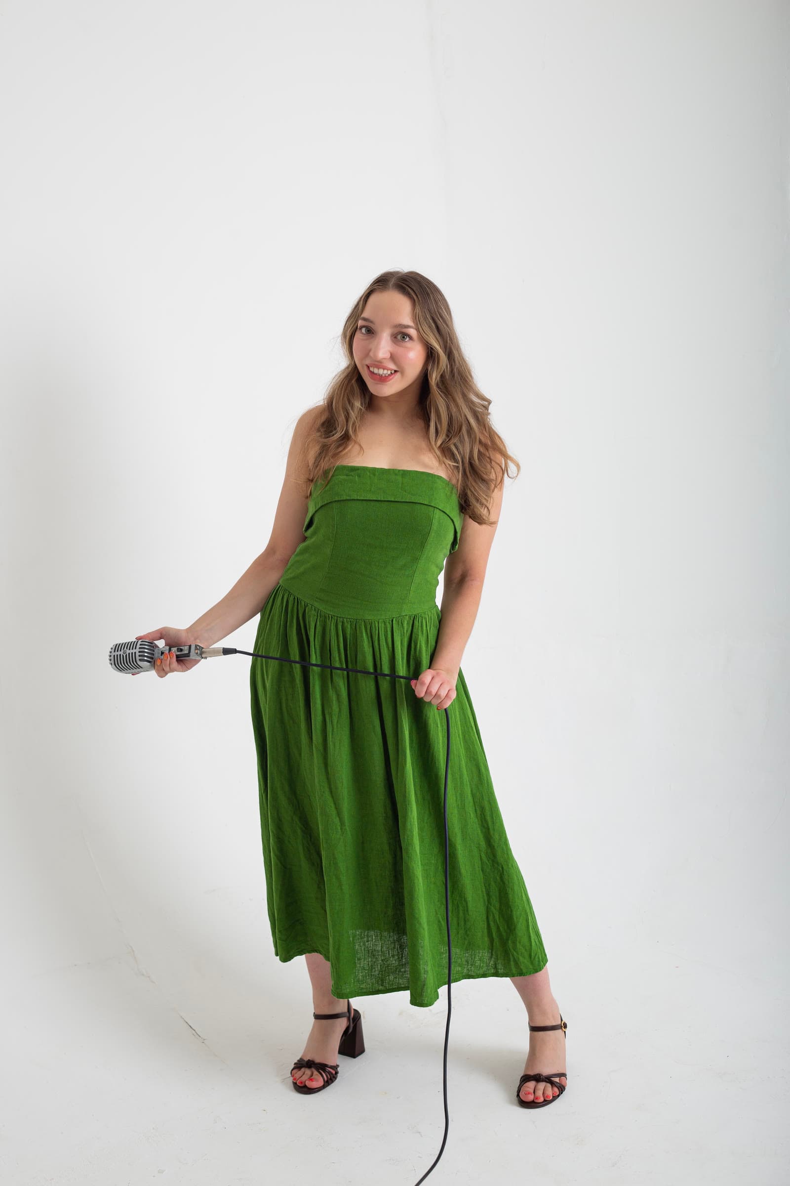 Olivia in a green dress holding a vintage microphone