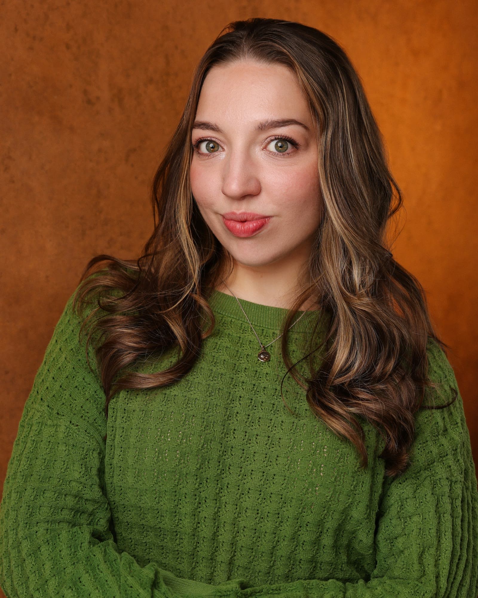 Portrait of Olivia Beall smiling, wearing a green jumper
